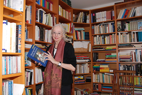 Elena Ostleitner in ihrer Hausbibliothek mit einem Buch in den Händen